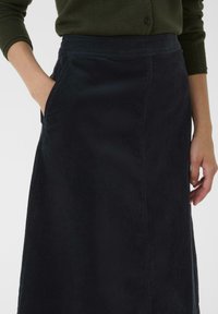 Gonna midi di velluto a coste blu navy con una texture liscia e tasche laterali, caratterizzata da una vita aderente e un taglio dritto.