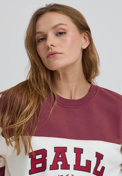 Felpa color bloc maroon e crema con collo a costine, con la scritta audace rossa "BALL" sul davanti, texture del tessuto liscia.