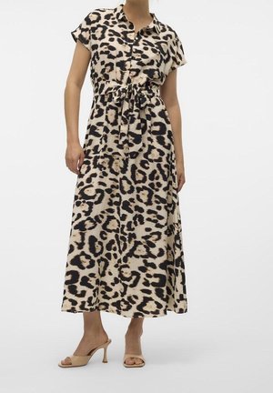 Vrouw draagt een beige midi-jurk met luipaardprint, korte mouwen, knopen aan de voorkant, tailleband en beige open-toe sandalen met hak.