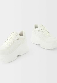 Sneaker platform bianche con finitura in pelle liscia, punta rotonda, design con lacci e suole in gomma rialzate con dettagli di cucitura sottili.