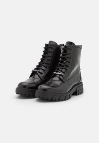 Czarne lakierowane buty na grubej podeszwie, z wiązaniami i bocznym zamkiem błyskawicznym. Posiadają białe logo "Hugo".