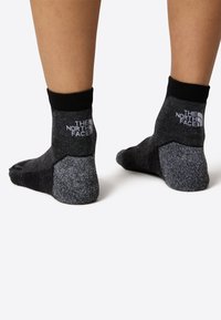 Czarno-szare skarpetki z wzmocnionymi piętą i palcami, z teksturowanym wzorem i logo na górnym pasku. W stylu do kostki.