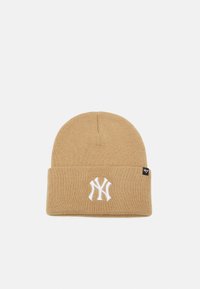 Gorro de punto beige con puño doblado, que presenta un logotipo bordado en blanco en la parte delantera y una etiqueta de marca negra en el lateral.