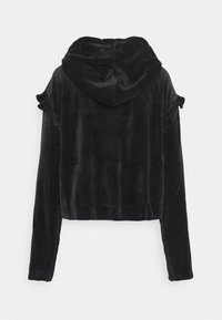 Svart kort hoodie i mjuk sammetstyg, med en stor huva och volangdetaljer på axlarna, långa ärmar med åtsittande manschetter.