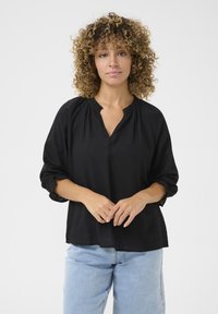 Schwarze Bluse mit V-Ausschnitt und gerafftem Hals, Dreiviertelärmel mit elastischen Bündchen, aus einem leichten Stoff gefertigt.