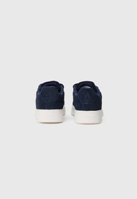 Adidași din suede bleu marin cu talpă din cauciuc alb, vârf rotunjit, guler căptușit și detaliu cu logo embosat pe toc.