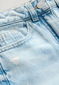 Ljusblå denimshorts med en blekt finish, en framficka och en liten reva vid nederkanten. Metallknappsstängning i midjan.