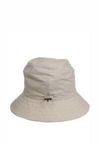 Beige keps i bucketmodell gjord av lättviktsmaterial. Har en smal, strukturerad skärm och en justerbar snodd med svart hårdvara på sidan.