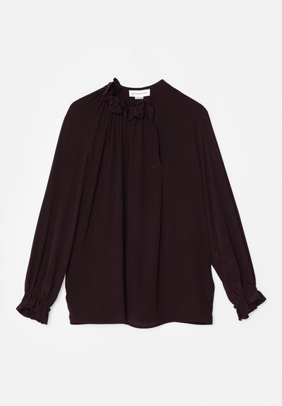 Blusa bordeaux scuro con scollatura arricciata e dettaglio a laccio, maniche lunghe con polsini arricciati, tessuto morbido e vestibilità ampia.