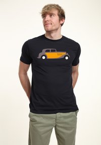 Černé tričko s krátkým rukávem s stylizovanou šedou a žlutou grafikou automobilu na přední straně. Hladký materiál, volný střih.