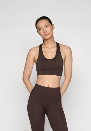 Soutien-gorge de sport marron côtelé et leggings taille haute, présentant un design sans couture et une texture douce, avec des bretelles larges et une silhouette ajustée.