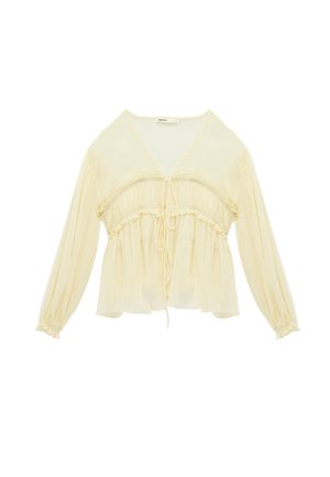 Cream-colored long-sleeve blouse with V-neck, gathered waist, ruffle details, and drawstring ties at front and sleeves.