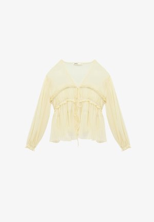 Cream-colored long-sleeve blouse with V-neck, gathered waist, ruffle details, and drawstring ties at front and sleeves.