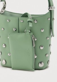 Πράσινη δερμάτινη τσάντα τύπου μπαντάνα με ασημένια καρφιά και προσαρτημένο ταιριαστό φερμουάρ σε λευκό φόντο.