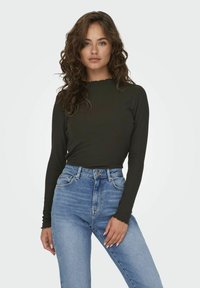 Long-sleeve ribbed top in dark green with a scalloped neckline, paired with high-waisted blue jeans featuring front pockets.