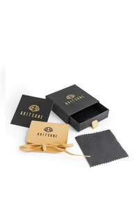 Scatola di cartone nera con logo dorato, un sacchetto in ecopelle scamosciata beige, un panno nero per lucidare e una scheda nera con il logo.