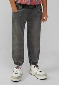 Pantalones jogger en gris con puños elásticos y bolsillos, combinados con zapatillas blancas y grises con acentos multicolores y cordones.