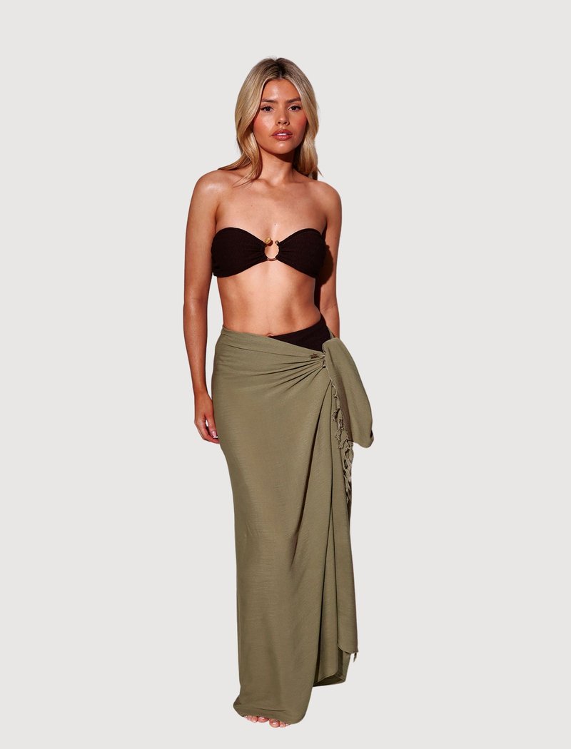 Haut bandeau noir avec accent doré et jupe portefeuille vert olive avec drapé et liens sur le côté, réalisée en tissu léger.