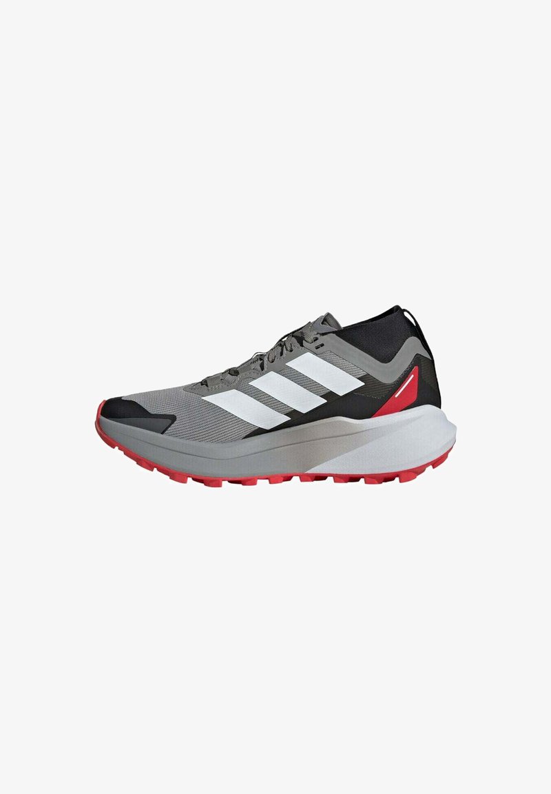 Baskets de sport grises et noires avec des rayures blanches, des accents rouges et une semelle rouge, conçues pour la course ou les activités sportives.