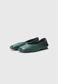Sapatilhas de balé em couro verde, com bico arredondado, salto baixo em cunha e textura suave, apresentando um design sem emendas e acentos minimalistas.