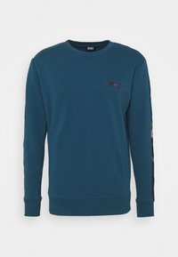 Teal sweatshirt med långa ärmar, ribbade muddar och rundad halsringning. Har en liten logotyp på bröstet och mönstrade detaljer på ärmarna.