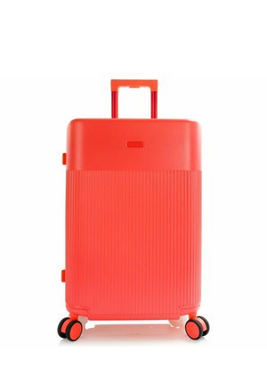 Valigia rigida rosso brillante con manico telescopico e quattro ruote doppie girevoli, in posizione verticale su sfondo bianco.