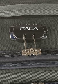 Candado combinado negro con el logo "ITACA", sujeto a una bolsa de tela oscura, con cremalleras duraderas y una textura sutilmente acanalada.