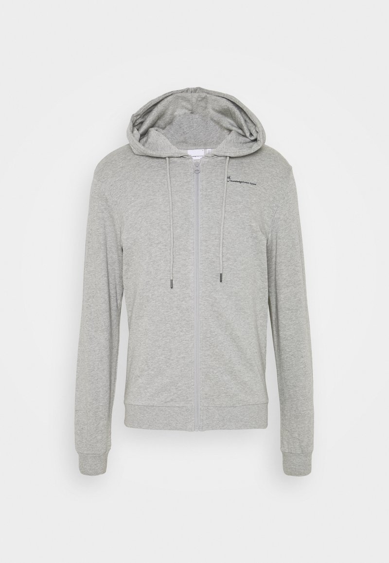 Sweat à capuche gris clair zippé avec cordons et manches longues, présentant un petit logo sur la poitrine gauche.