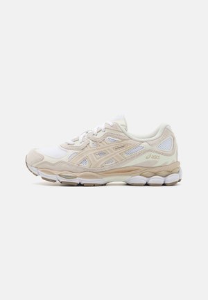 Beige und weiße Asics Laufschuhe mit Mesh-Einsätzen, strukturierter Sohle und Logo an der Seite, von der Außenseite vor hellem Hintergrund gezeigt.