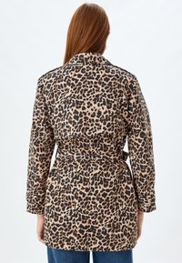 Abrigo de tela de estampado de leopardo con cintura ceñida, cuello con muesca y mangas largas. Material texturizado y ligero con manchas de color marrón oscuro y negro.