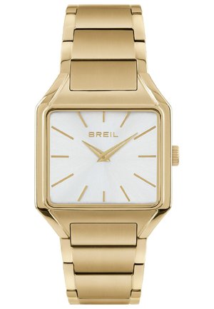 Guldtonet firkantet ur med en hvid tekstureret skive, guld timemarkeringer og et kædearmbånd. Brandlogoet er synligt ved kl. 12.