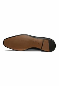 Black leather shoe sole with a smooth finish, featuring a brown rubber layer at the heel and gold accent studs near the arch.