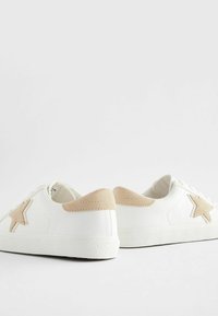 Sneakers bianchi in pelle con suola testurizzata, caratterizzati da una stella beige e un patch sul tallone, che presentano un design con lacci.