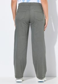 Pantalons à jambe large en tissu vert olive. Dotés de poches arrière et d'une coupe décontractée. Design uni sans motifs ni quincaillerie visible.