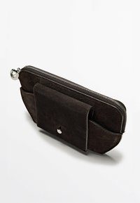 Pochette en daim marron avec fermeture à glissière argentée, dotée d'une poche avant et d'une forme arrondie, texture lisse et détails de conception minimalistes.