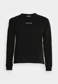 Felpa nera a manica lunga realizzata in materiale morbido, con collo a giro e una vestibilità rilassata, decorata con un logo bianco "Calvin Klein" sul petto.