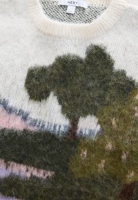 Pull en tricot avec un fond texturé crème clair, motifs de paysage verts et roses ; matière en laine douce et duveteuse ; col rond.