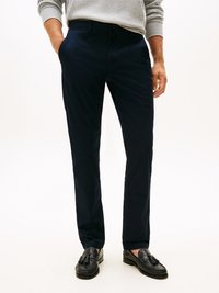 Pantaloni dritti blu navy realizzati in tessuto morbido, con tasche frontali e una cintura liscia. Indossati con mocassini in pelle nera.