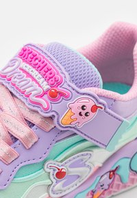 Színes sneaker lila, rózsaszín és menta mintával, fagylalt témájú részletekkel és texturált anyagokkal. Kiemelkedő logó a nyelven.