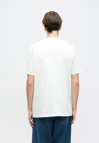 T-shirt branca de algodão com um corte standard e mangas curtas, apresentando um decote redondo e uma textura suave. Sem padrões ou gráficos visíveis.