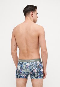 Heren boxershorts in een bloemmotief, met een groene tailleband met merknaam. Het materiaal lijkt rekbaar met een aansluitend ontwerp.