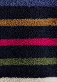Fleece blanket featuring horizontal stripes in navy, brown, pink, green, and cream. The texture is soft and fluffy.