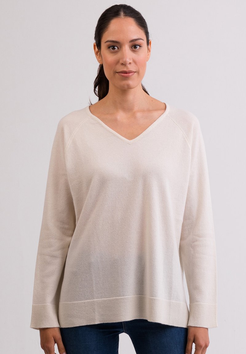 Cremefarbener V-Ausschnitt-Pullover mit langen Raglanärmeln, geripptem Saum und weicher Textur. Lockere Passform, die sich gut zum Überziehen über andere Kleidung eignet.