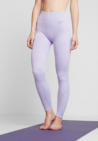 Leggings sportivi di colore viola chiaro con vita alta, texture a coste e dettagli a taglio lungo i fianchi. Logo Nike sulla cintura.