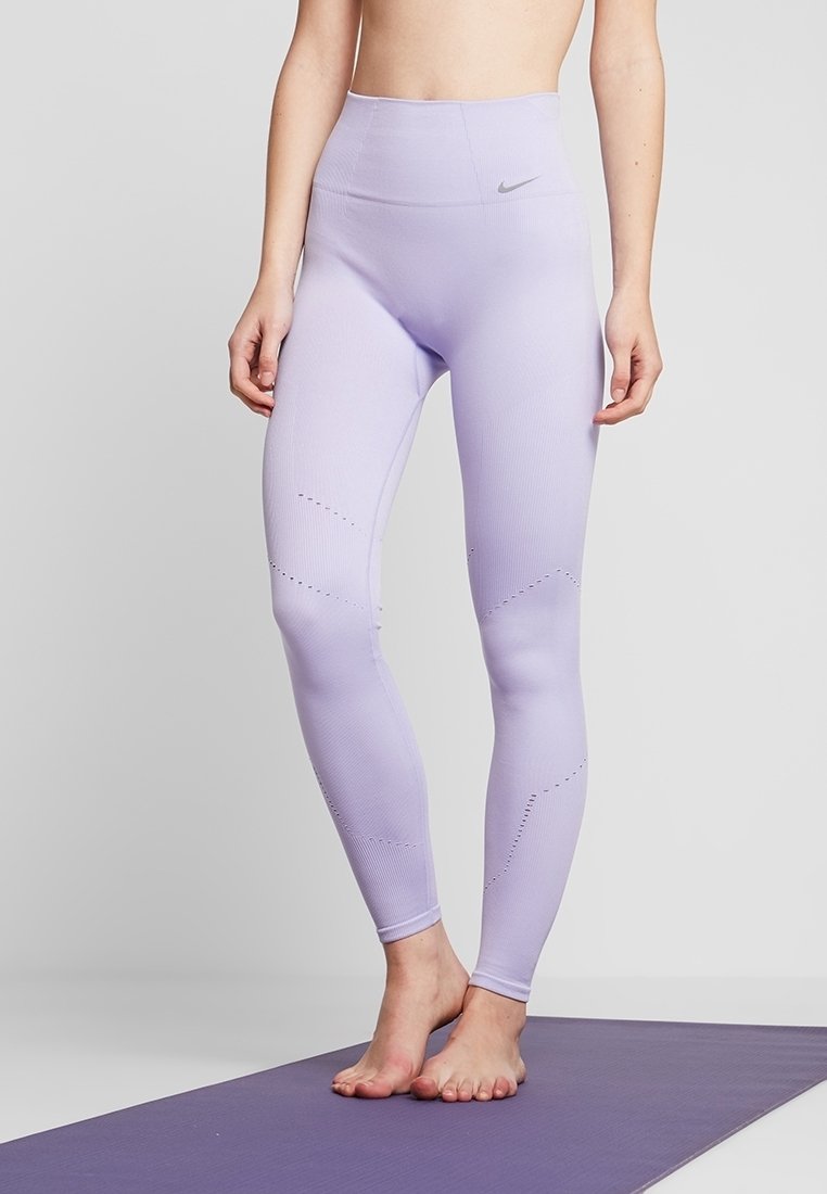 Leggings sportivi di colore viola chiaro con vita alta, texture a coste e dettagli a taglio lungo i fianchi. Logo Nike sulla cintura.