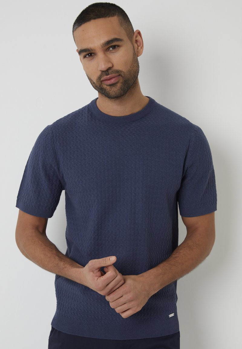 Kurzarmpullover aus navyblauem Strick mit strukturiertem Muster, geripptem Rundhalsausschnitt und kleinem Logodetail am Saum.