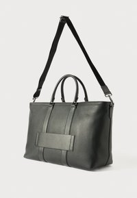 Černá kožená taška přes rameno s horními úchyty a odnímatelným ramenním popruhem. Obsahuje texturovaný povrch a obdélníkový akcent na přední straně.