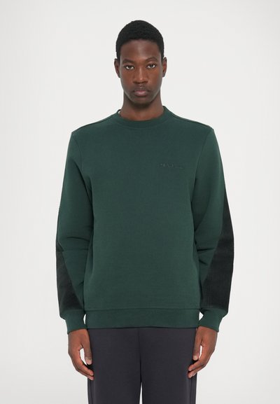 Mørkegrøn sweatshirt med teksturerede sorte sidepaneler, ribbede manchetter og rund halsudskæring; har diskret logo-broderi på brystet.