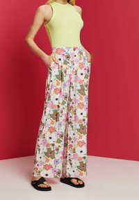 Wijdvallende broek met bloemenpatroon in het wit, met accenten in roze, groen en paars. Gelaagde stof met zijzakken en een knoopsluiting.