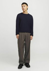 Suéter de punto azul marino con cuello redondo, combinado con pantalones gris con pliegues y zapatos negros de suela gruesa, presentando un corte relajado y una textura suave.